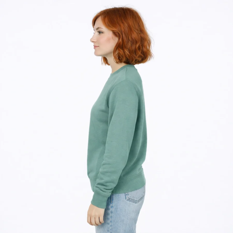 Red-haired woman wearing a green sweatshirt and light-wash jeans.
