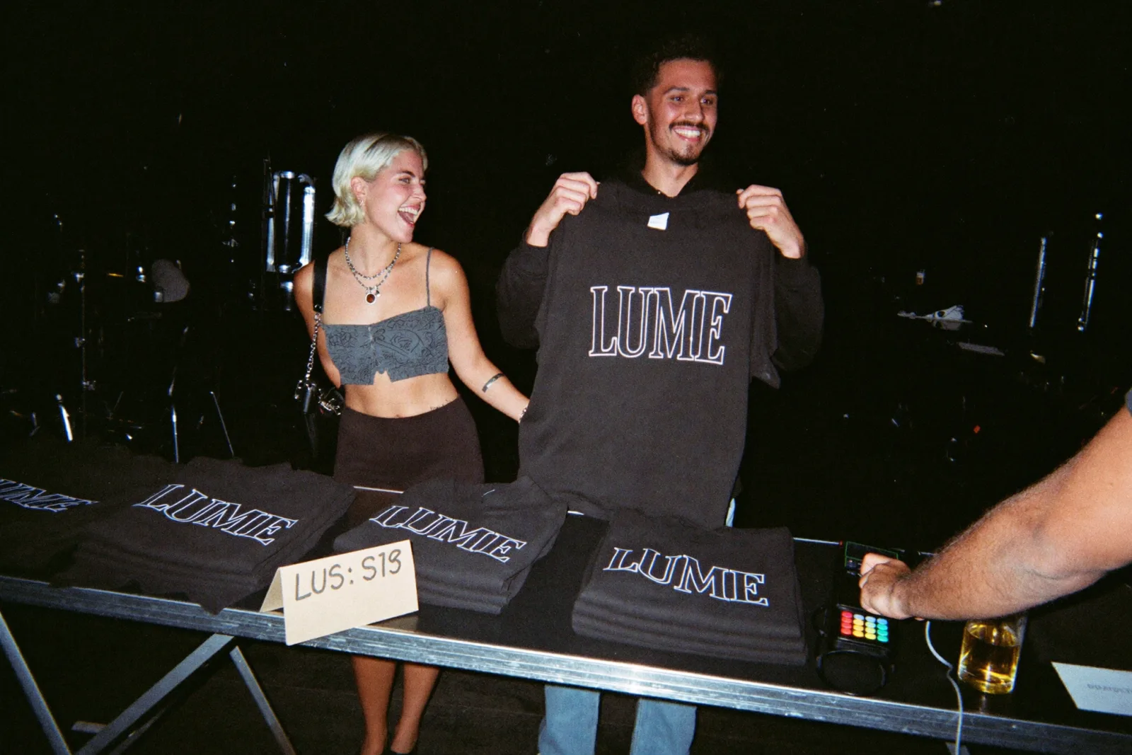 Banca de merch num concerto, com t-shirts e hoodies pretos com o logótipo da banda