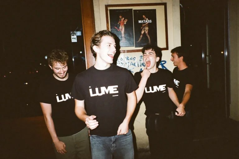 Merch para bandas: quatro músicos de t-shirt preta com o logótipo da banda, à porta da sala depois do concerto