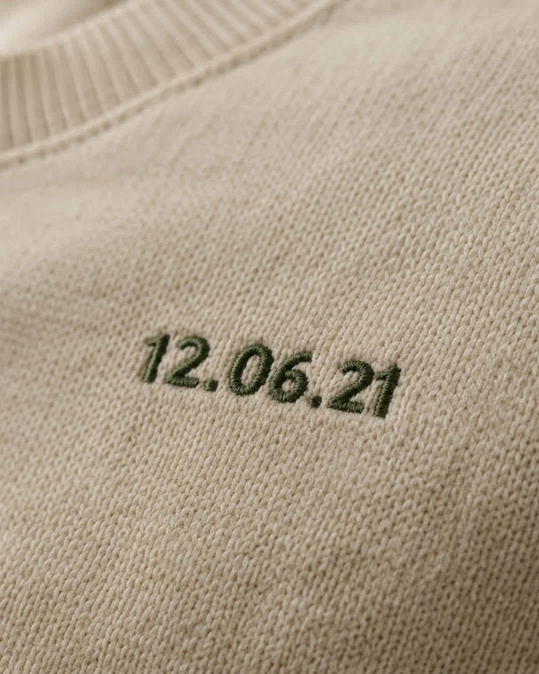 Detalhe de uma data bordada a verde numa sweat cor creme